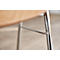 Gros plan sur un pied de chaise. Les pieds sont en métal chromé, reliés par une entretoise horizontale. L'assise est brun clair, en bois.