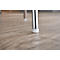 Gros plan sur un pied de chaise en métal posé sur un sol en bois. La jambe est munie d'un capuchon en plastique de couleur claire.
