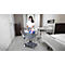 Nurse with a mask pushing a cart through a hospital room. Medical items are in the cart.