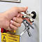 Main tenant une clé multifonction sur fond blanc. Sur un panneau, il est écrit : Attention ! L'interrupteur principal et l'arrêt d'urgence ne déconnectent pas l'installation.