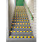 Staircase with yellow and black warning stripes, green handrail, green door.