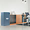Coffre-fort bleu devant un mur clair. Mobilier de bureau, bureau et chaise en arrière-plan.