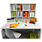Bureau avec fournitures de bureau : dossiers, plateaux, lampe, tasse et téléphone. Une chaise devant, une étagère derrière.