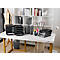 Bureau avec articles d'organisation de bureau : plateaux à papier, porte-stylos, corbeille. Table blanche, bibliothèque derrière.