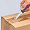 Une main coupe un carton avec un couteau KNIPEX rouge et bleu.