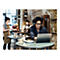 Mann mit Brille und KopfhÃ¶rern, der an einem Laptop in einem CafÃ© sitzt, lÃ¤chelt.
