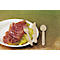 Une assiette de prosciutto, de melon et de couverts en bois.