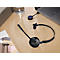 Black headset and accessories on a table. Laptop in the background.