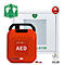 Roter Defibrillator mit Griff. Aufschrift: AED. Daneben Hinweisschilder und Piktogramme.