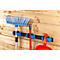 Broom, shovel and dustpan set in blue holders on a wooden plank wall.