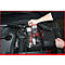 Ein rotes Multimeter misst die Spannung an einer Autobatterie. Das Display zeigt 12,41 V an. Das Bild zeigt den Motorraum eines Autos.
