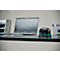 Black electronic stapler on desk next to laptop, tablet and pens. Green and blue LEDs are illuminated on the stapler.