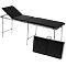 Table de massage noire avec têtière réglable et valise de transport pliée.