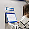 Eine Person betrachtet ein Zustandsdiagramm in einer blauen Dokumententasche an einer Whiteboard-Wand.