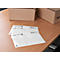 Three transparent envelopes lie on a wooden table. Cardboard boxes in the background.
