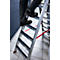Person is climbing a silver ladder. Black shoes on non-slip steps. Red stripe on the floor.