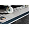 Close-up of a wheelchair ramp featuring a white wheel and a black non-slip strip. The surface is made of corrugated metal.