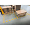 Stacks of cardboard on pallets in a warehouse, yellow markings on the floor.
