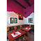 Gezellige restaurant hoek met roze muur, wit baksteen, gestoffeerde banken en houten tafels.