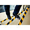 Person walking up stairs; the steps have black and yellow stripes.