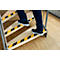Person climbing stairs. Yellow and black warning stripes on the steps, light wood look, jeans and black shoes.
