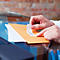 Des mains collent une étiquette sur une enveloppe. Il y a du texte sur l'étiquette.