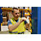 A man in a yellow safety vest attaches a tape to a warehouse pole. In the background, shelves with boxes are visible.