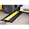 Black cable bridge with yellow stripe, forklift driving over it, cables inside.