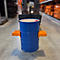 Blauer Metallfass, in orangefarbener Halterung, auf einem Gabelstapler. Lagerhalle im Hintergrund.