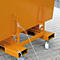 Detailansicht eines orangefarbenen Metallbehälters mit Rädern und Sicherungsseilen. Der Behälter steht auf Pflastersteinen.