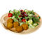 Teller mit Falafel, Salat, Tomaten, Gurken und Granatapfelkernen.