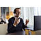 A man with a headset sits in front of a laptop, gesturing with his hands during a video call.