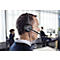 Man wearing a headset in the office. The man is wearing a dark sweater. Other people are sitting in the background.