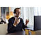 A man wearing a headset gestures with his hands in front of a laptop.