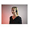 Eine blonde Frau mit Headset, schwarzem Oberteil, vor einem roten Hintergrund.