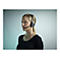Junge Frau mit blonden Haaren trÃ¤gt ein Headset mit Mikrofon. Sie blickt zur Seite, vor hellem Hintergrund.