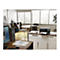 Büro mit Drucker auf Schrank. Auf dem Schreibtisch liegen Dokumente und ein Computer. Im Hintergrund sind Stühle und ein Tisch zu sehen.