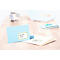 Enveloppe bleu clair avec autocollant d'adresse "Mr. Sunny" sur une table en bois. En arrière-plan : ordinateur portable et bloc-notes.