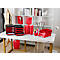 Bürotisch mit roten Büroaccessoires: Ablagen, Ordner, Papierkörbe. Hintergrung: weisses Regal mit Büchern, eine Schaufensterpuppe.