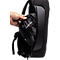 Eine Hand öffnet die Reißverschlusstasche eines schwarzen Rucksacks und zeigt einen schwarzen Beutel mit einem reflektierenden Streifen.