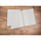 Livre gris avec un design doré sur une table en bois, ouvert.