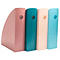 Quatre porte-magazines colorés se tiennent côte à côte. Chacun a un trou et est en rose, turquoise, beige et bleu clair.