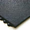 Close-up of a black rubber floor tile with textured surface and connector pins on the edges.