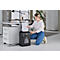 A young woman kneels, feeding paper into a shredder.