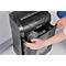 Person opening the waste bin of a black paper shredder. The bin is filled with shredded paper. "Fellowes" is visible on the device.