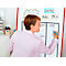 Eine Frau schreibt mit blauem Stift auf ein Whiteboard. Auf dem Board stehen Namen und Aufgaben, wie 'Budget'.
