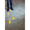 A child stands over yellow footprints on a gray floor. They are wearing jeans and black shoes with red accents.