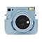 Hellblaue Instax Sofortbildkamera in einer passenden Ledertasche, Frontansicht, weißer Hintergrund.