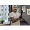 Un tatoueur souriant dans un studio de tatouage en train d'enfiler des gants noirs.