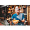 Un chef en veste et bonnet de cuisine bleus, souriant et tenant un bol de ramen.